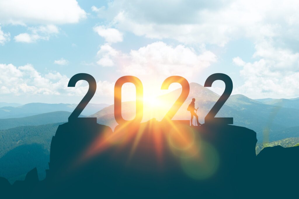 The number 2022 is perched atop a mountain with a man standing at the top