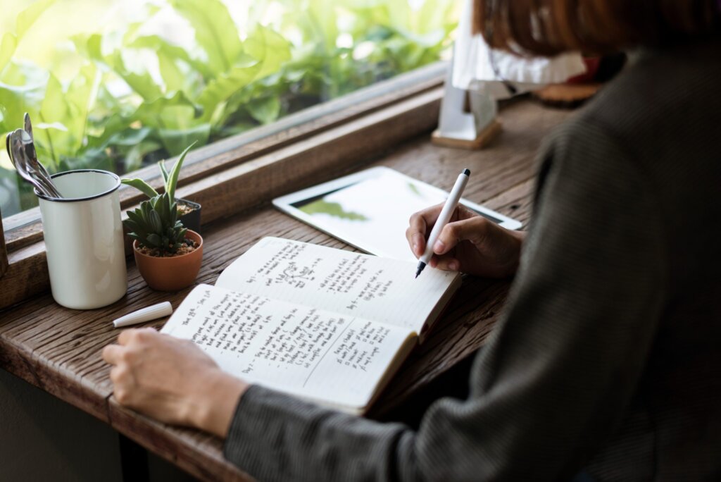 person writing in journal for better productivity