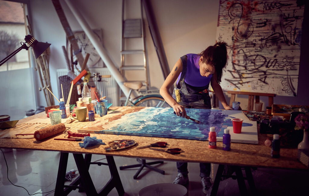 A person uses a palette knife to paint in a studio